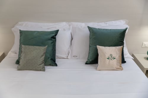 Letto elegantemente arredato ad Altavilla Boutique a Marsala con cuscini verde e panna su biancheria bianca