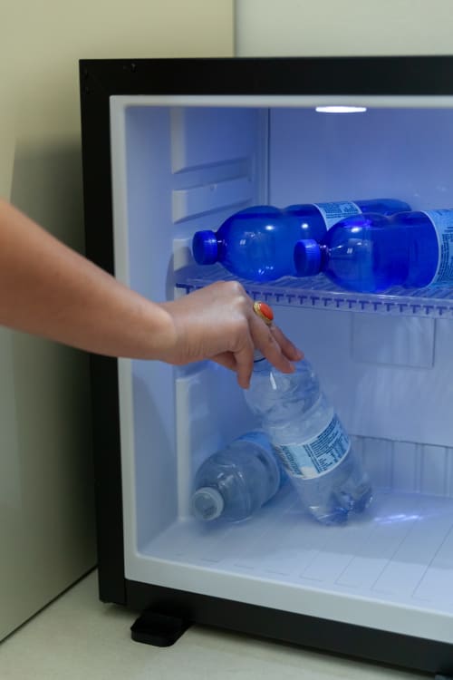 Ospite che preleva bottiglie d'acqua blu dal minibar nella Standard Room di Altavilla Boutique Holidays House, Marsala