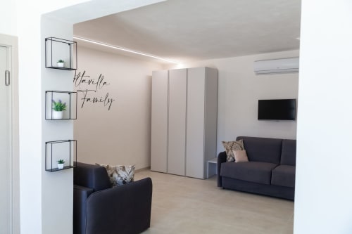 Modern living room in Marsala B&B with black sofas, wall shelves, white storage, and 'Hamily' sign decor