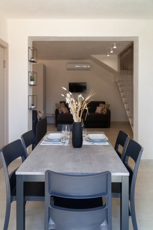Modern dining area with black chairs, set table, and staircase leading to living room with sofa at Altavilla Boutique in