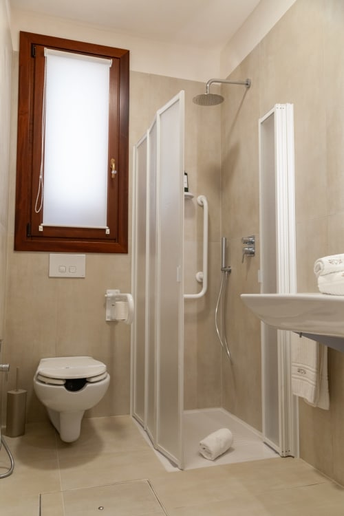 Accessible bathroom with walk-in shower, toilet, white grab bars, and modern amenities at Altavilla Boutique Holidays House,