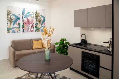 Modern studio at Altavilla Boutique Holidays House in Marsala with beige sofa, round table, tropical artwork, and compact