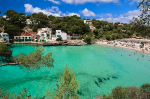 Cala turquesa con playa, villas blancas y embarcaciones en Colonia de Sant Jordi