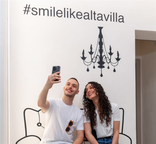 Couple taking selfie at Altavilla Boutique Holidays House in Marsala with decorated wall and chandelier