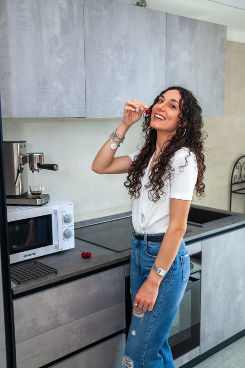 Woman smiling in modern kitchen at Altavilla Boutique Holidays House, Marsala with appliances and gray cabinetry