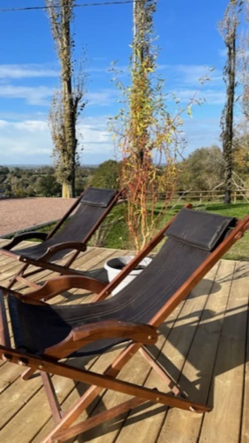 Deux chaises longues sur une terrasse en bois du Domaine de Blanvatel avec vue sur la campagne