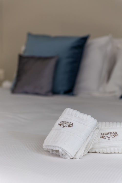 Calzini bianchi Altavilla Boutique sul letto con cuscini, amenità dell'hotel Marsala