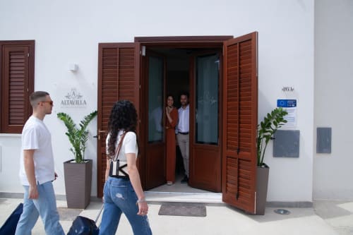 Guests arriving at Altavilla Boutique Holidays House entrance in Marsala with red wooden doors and potted plants