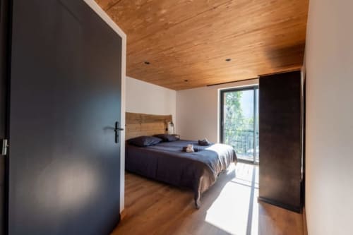 Chambre moderne au Domaine de l'Epigny avec plafond en bois, lit noir et balcon vue sur Grand Aigueblanche