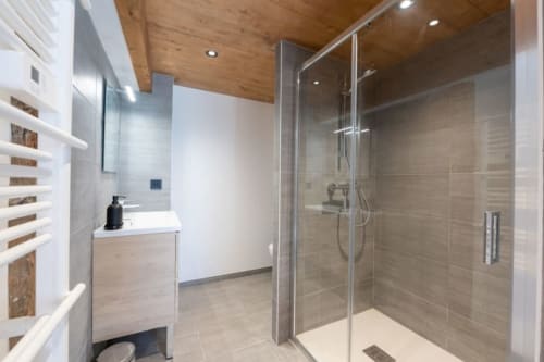 Salle de bains moderne à la Domaine de l'Epigny avec douche à l'italienne, vasque, et plafond aux détails en bois
