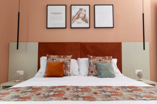 Camera boutique ad Altavilla a Marsala con testata in terracotta, cuscini floreali e opere d'arte incorniciate