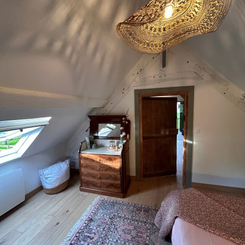 Chambre mansardée au Domaine de Blanvatel avec mobilier en bois, applique en laiton ouvragé et plafonds inclinés à Saint Pierre