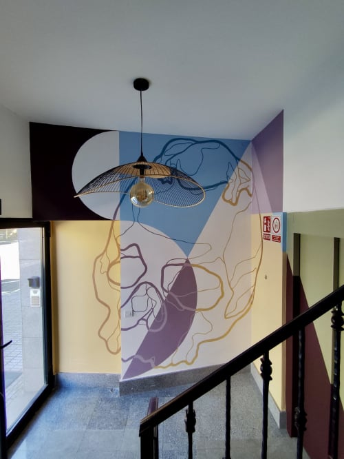 Lámpara colgante moderna sobre obra anatómica en escalera de apartamento de Salamanca con mural artístico