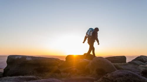 Escursionista con zaino in silhouette al tramonto su terreno roccioso vicino a Roccasecca, Italia