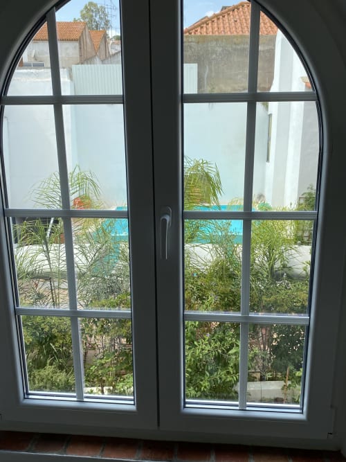 Vista do jardim através de portas em arco na Patio Da Villa, pousada em Coruche com plantas tropicais e terraço