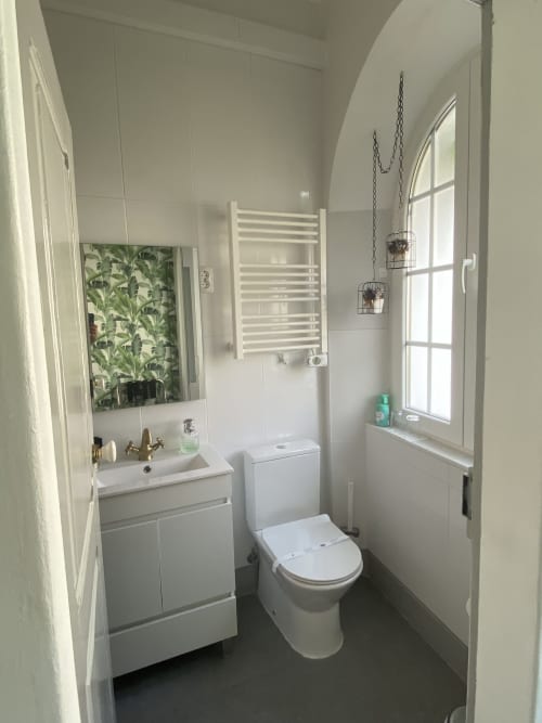 Banheiro moderno branco com pia, vaso sanitário, toalheiro aquecido e janela em arco na pousada Patio Da Villa Coruche