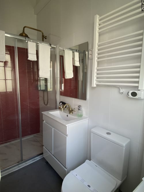 Casa de banho moderna em-suite na Patio Da Villa Coruche com chuveiro de azulejo vermelho, móvel lavatório branco, sanita e toalheiro aquecido