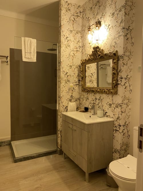 Luxurious bathroom at Patio Da Villa with floral wallpaper, wooden vanity, ornate mirror, and walk-in shower at Coruche guest