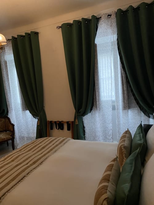 Deluxe bedroom at Patio Da Villa Coruche with green drapes, striped bedding, and sheer curtains at windows