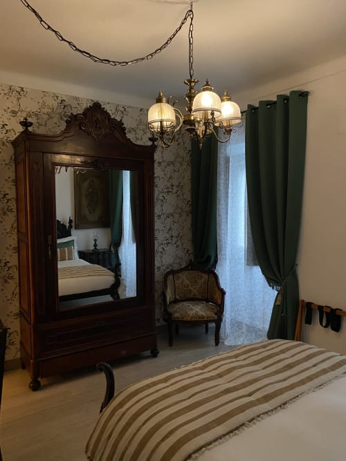 Elegant bedroom at Patio Da Villa with ornate wardrobe, chandelier, striped bedding, and green curtains in Coruche guesthouse