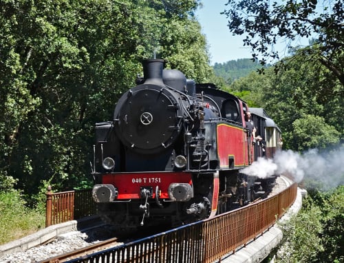 Ancienne locomotive à vapeur sur des rails courbes près de La Romance, Bagard, France, entourée d'une forêt verte luxuriante