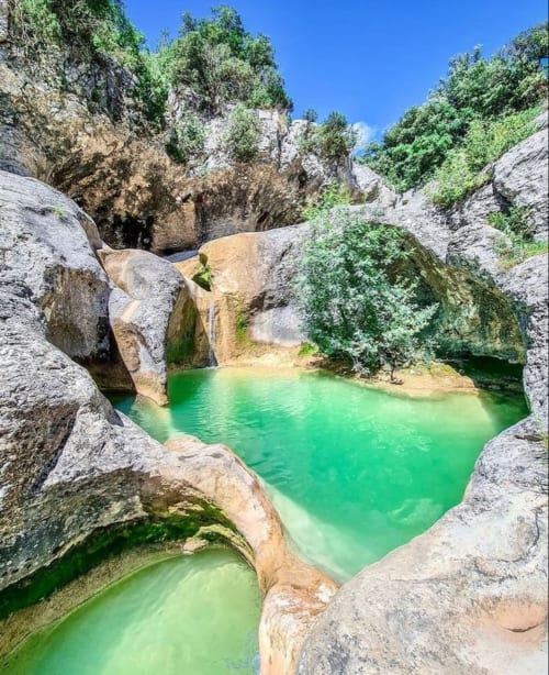 Piscines naturelles d'eau émeraude entourées de roches calcaires à La Romance, Bagard France