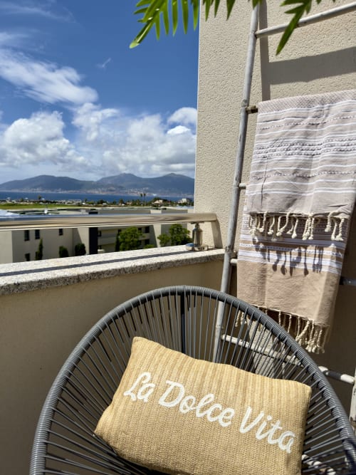 Balcon de l'hôtel SoleMare avec coussin jaune, plaid rayé, vue sur le lac et les montagnes depuis Alata