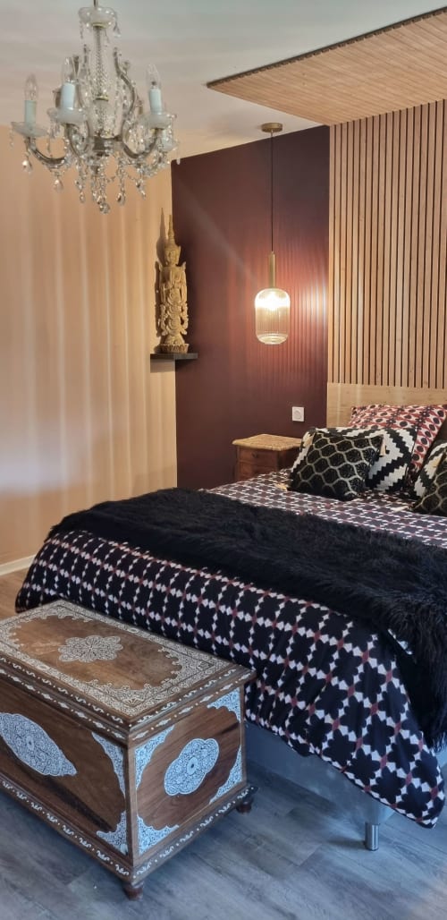 Suite élégante aux Forges Du Lou avec mur d'accent bordeaux, lustre en cristal et literie à motifs
