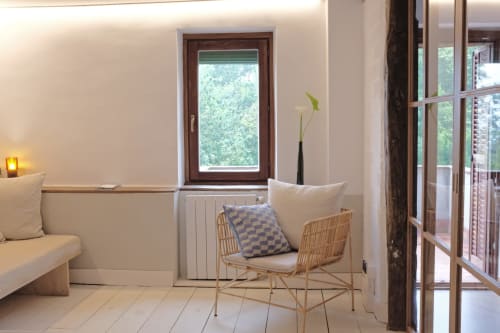 Luminosa zona de estar en apartamento rural MAÑARINEGI Gipuzkoa con silla de mimbre, ventanal con vistas al jardín y calefacción moderna