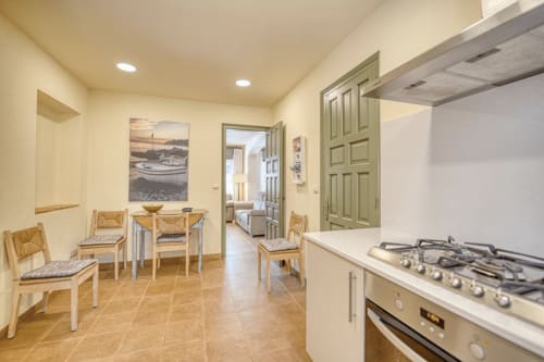 Modern kitchen and dining area in beachside cottage near Palafrugell with gas stove, white counters, and wooden chairs
