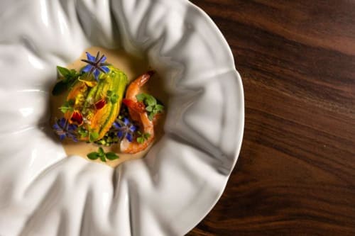 Élégant plat de crevettes dressé avec légumes colorés et fleurs comestibles à La Romance, Bagard