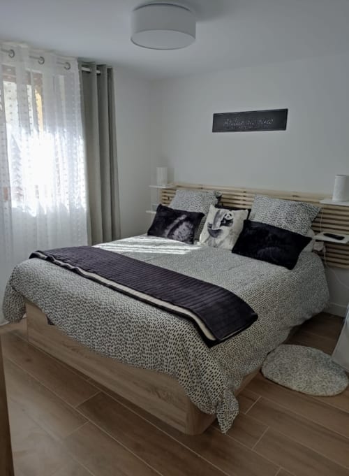 "Chambre parentale de l'appartement à Vars-les-Claux, équipée d'une tête de lit en bois, placards intégrés et salle de bain attenante, offrant un espace intime et confortable pour un séjour montagnard."
