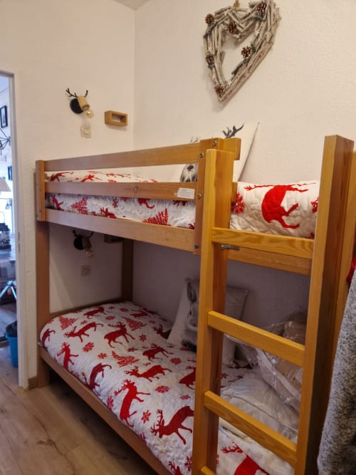"Coin nuit de l'appartement à Vars-les-Claux, avec 2 lits superposés décorés dans les couleurs de Noël, créant un espace chaleureux et festif, parfait pour les enfants ou les amis pendant la saison hivernale."
