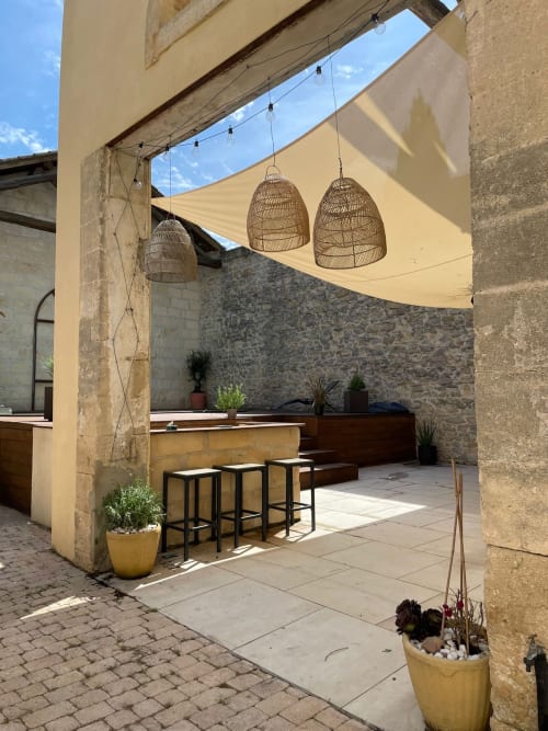 Outdoor-Essbereich der Villa La Conciergerie De Franck mit geflochtenen Pendelleuchten und Sonnensegel