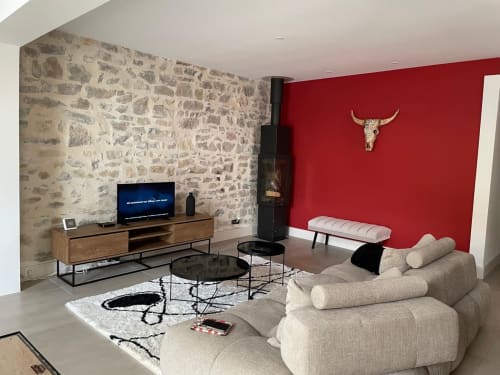 Modernes Villenwohnzimmer mit beigem Ecksofa, roter Akzentwand, Steinkamin und Flachbildschirm in La Conciergerie