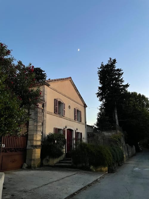 Historische Steinvilla La Conciergerie De Franck in Boissieres mit cremefarbener Fassade, roten Fensterläden, umgeben von üppiger Begrünung