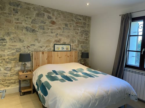 Rustikales Steinschlafzimmer mit Holzkopfteil, moderner Bettwäsche und französischen Fenstern in der Villa La Conciergerie De Franck