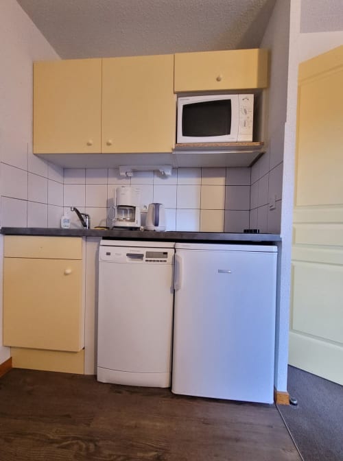 Cuisine lumineuse de l'appartement 701 à Vars-les-Claux, avec des accents de couleur jaune, offrant un espace moderne et accueillant pour préparer des repas après une journée en montagne."