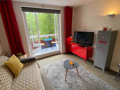 "Vue du salon et du balcon de l'appartement 776 à Vars-les-Claux, offrant un espace lumineux avec accès direct à l'extérieur, idéal pour profiter du paysage montagnard depuis le confort du salon."