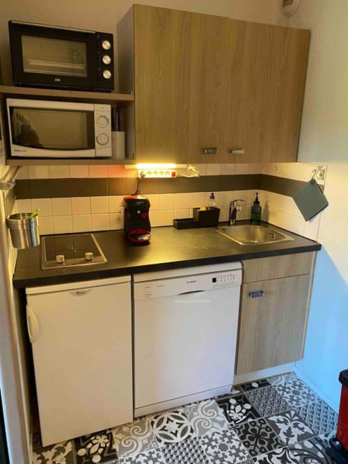 "Cuisine de l'appartement 776 à Vars-les-Claux, au design élégant combinant bois naturel et accents noirs, créant un espace moderne et chaleureux pour préparer des repas après une journée en montagne."