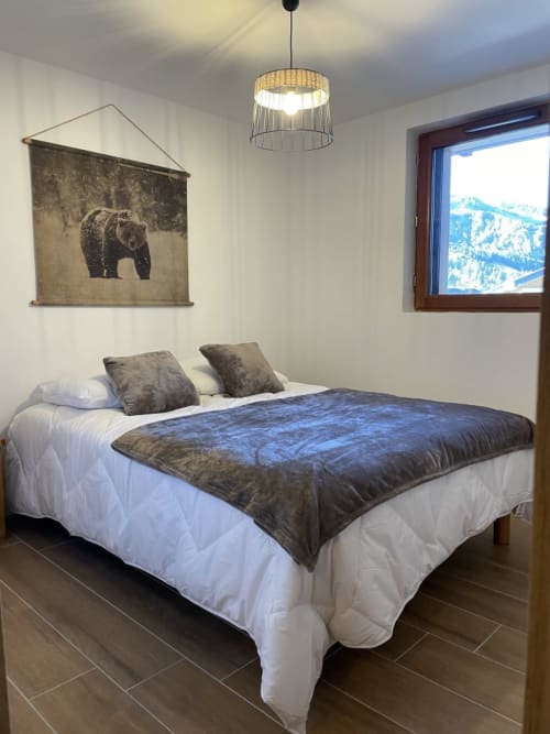 "Chambre rustique de l'appartement 203 à Vars-les-Claux, décorée avec des éléments en bois naturel et un style montagnard chaleureux, offrant un espace cosy et authentique pour un séjour reposant."