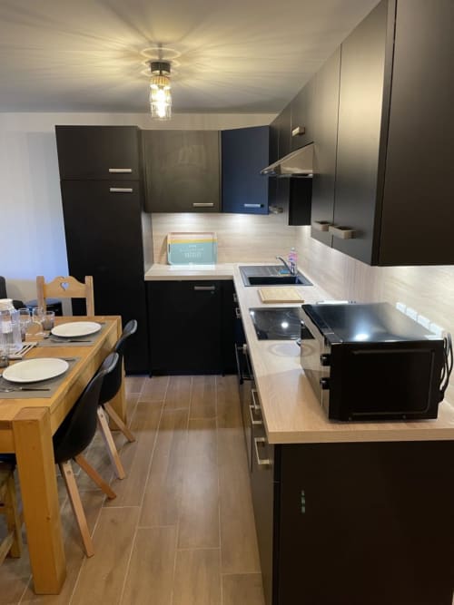 "Vue alternative de la cuisine noire chic de l'appartement 203 à Vars-les-Claux, montrant l'élégance des finitions et le design contemporain, parfait pour un séjour alliant style et confort."