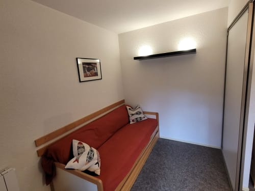 "Vue d'une partie du salon de l'appartement 553 à Vars-les-Claux, montrant un canapé convertible qui se transforme en lit double, offrant une solution pratique pour créer un espace chambre supplémentaire en un clin d'œil."