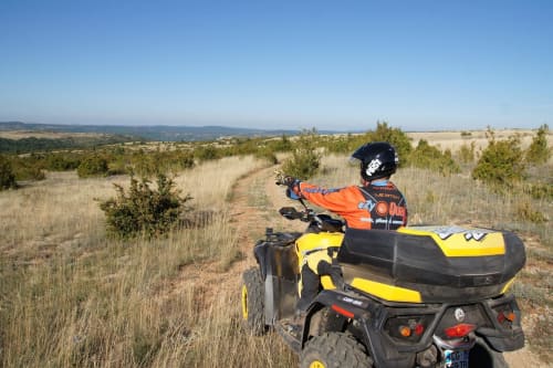 Motocycliste en veste orange sur quad jaune surplombant les collines ondulantes près de Bagard, France