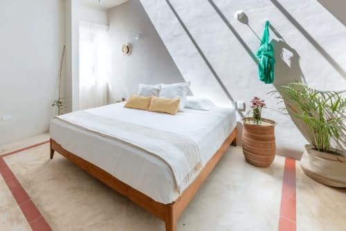 Luminosa habitación en ático de Casa Tuch B&B en Mérida con cama de madera, ropa blanca, almohadas amarillas, plantas y luz natural