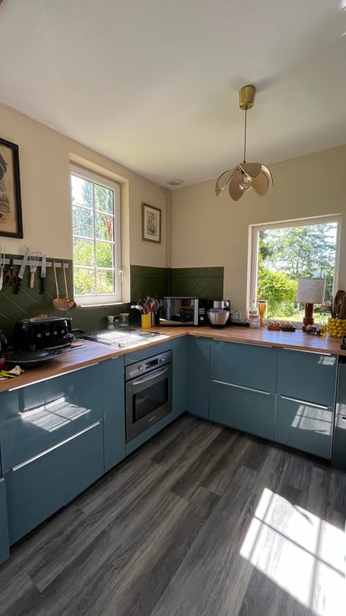 Modern kitchen at Domaine de Blanvatel B&B in Saint Pierre en Auge with teal cabinets, wood countertops, and garden views