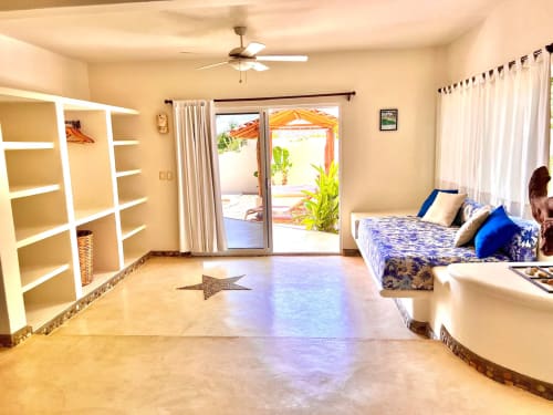Habitación luminosa en Calilla & Tsuki Puerto Escondido con ropa de cama azul, estantes blancos, ventilador de techo y patio con vista al océano