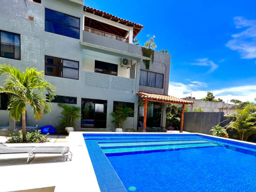 Piscina Calilla & Tsuki y edificio moderno blanco con palmeras en Puerto Escondido