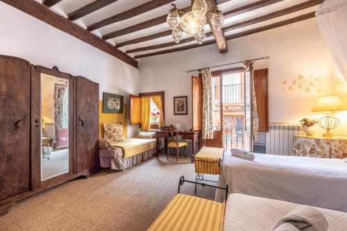 Spacious Santiago room at Casa Peregrinando B&B in Navarrete with exposed beams, twin beds, wooden wardrobe, and city views.