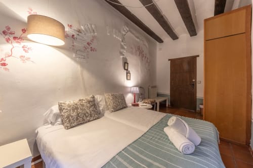 Chambre douillet à Casa Peregrinando à Navarrete avec poutres en bois, murs blancs, décor floral et vue sur la ville